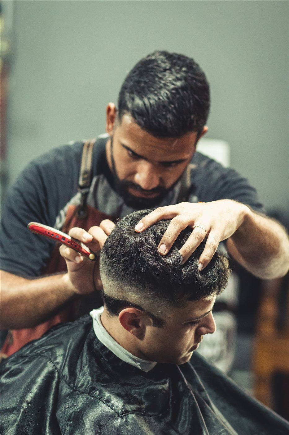 Barbero realizando un corte a un cliente en una barbería de estilo clásico