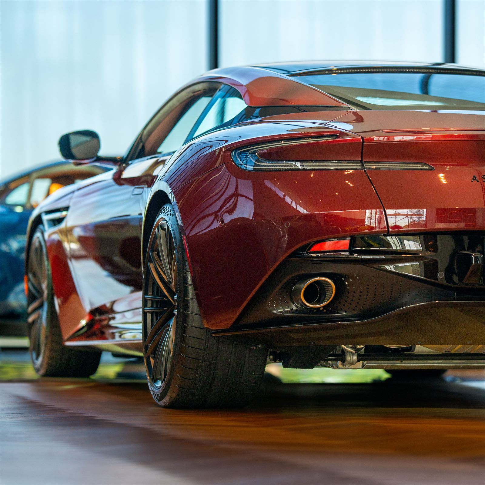 Gran turismo deportivo de color rojo profundo, vista trasera tres cuartos