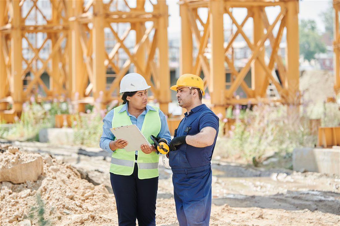 Equipo en obra revisando planos con chalecos de seguridad