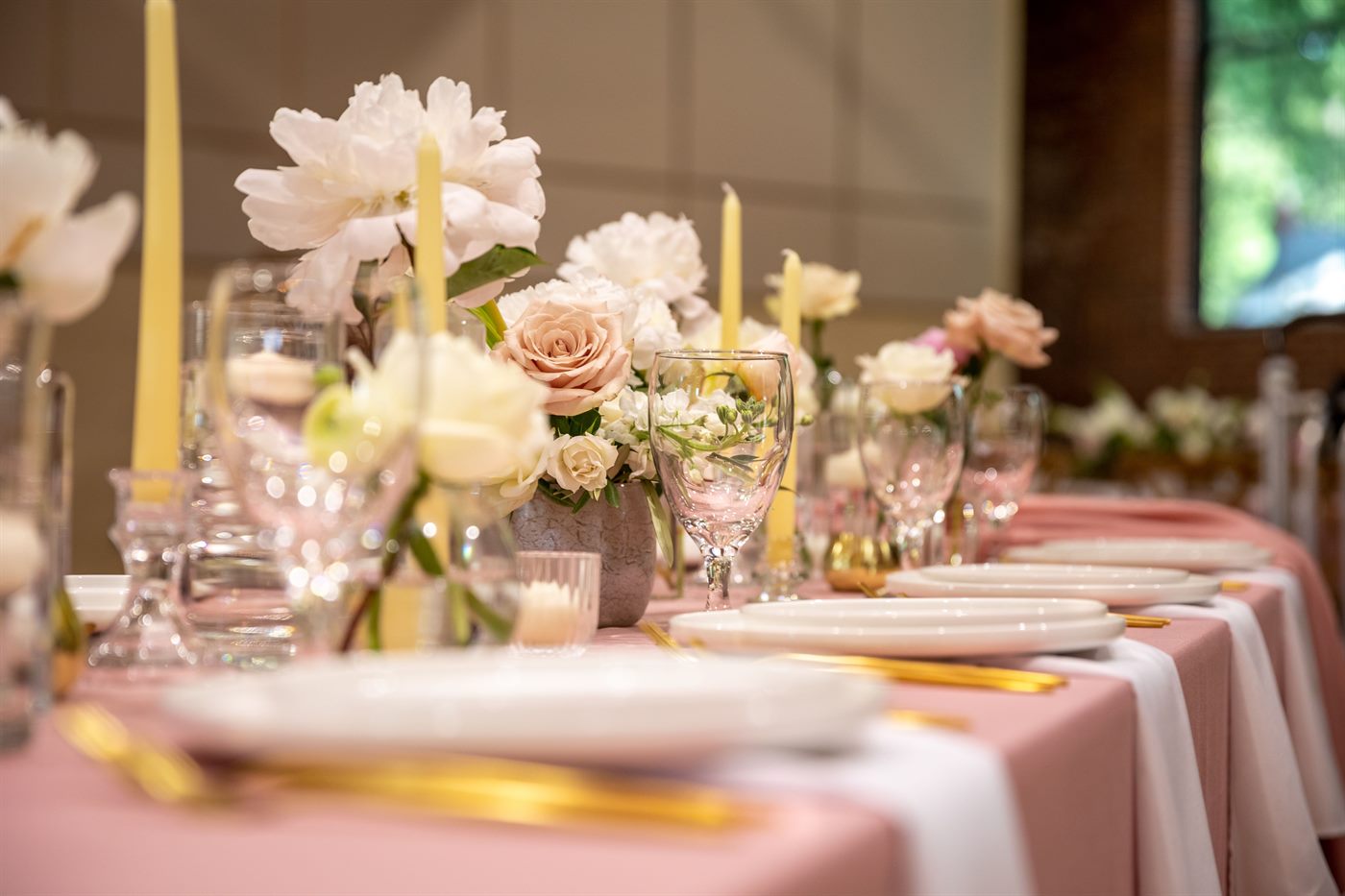 Mesa de banquete de boda con mantel rosa, centros florales y velas